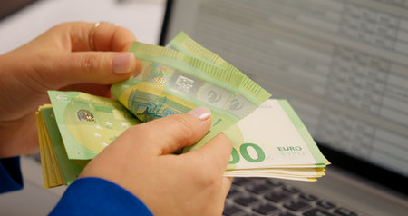 Rich woman enjoying euro banknotes in hands by counting them in special way. Family budget being...