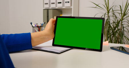 Close up chorma key horizontal tablet screen used by female worker. Woman using tablet sitting at desk browsing Internet.の写真素材