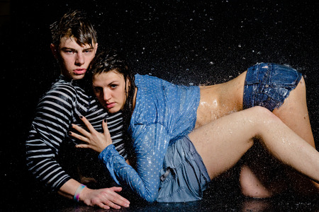 Young beautiful couple portrait in wet shirts on a black backgroundの写真素材