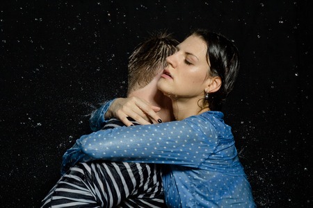 Young beautiful couple portrait in wet shirts on a black backgroundの写真素材