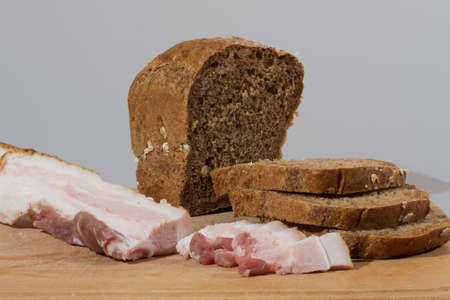 Lard with rye bread in the seeds on a wooden board, on a gray backgroundの写真素材
