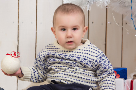 Baby boy under Christmas holiday fir tree with decorations and giftsの写真素材