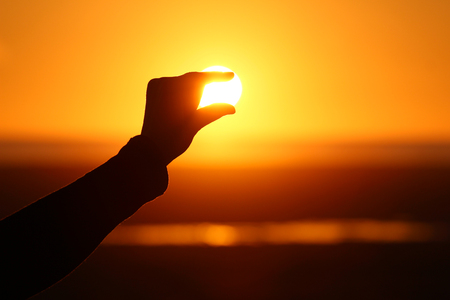 Silhouette of hand and fingers at sunsetの写真素材