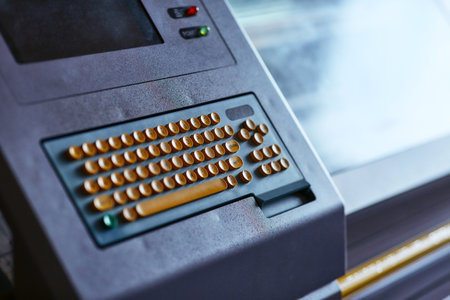 Built-in color keyboard with yellow mechanical buttons for the computer of a large industrial knitting machine with a built-in monitor next to itの写真素材