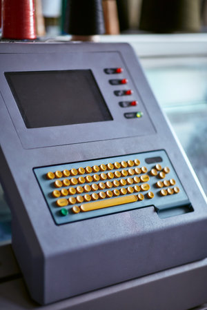 Built-in color keyboard with yellow mechanical buttons for the computer of a large industrial knitting machine with a built-in monitor next to itの写真素材
