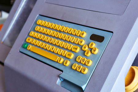 Built-in color keyboard with yellow mechanical buttons for the computer of a large industrial knitting machineの写真素材