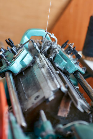 A small simple knitting machine with threads nearby without workersの写真素材
