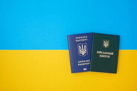 Ukrainian green military ID ticket on the Ukrainian national flag in the top view. Translation: "Military ID" and blue Ukrainian biometric IDの写真素材
