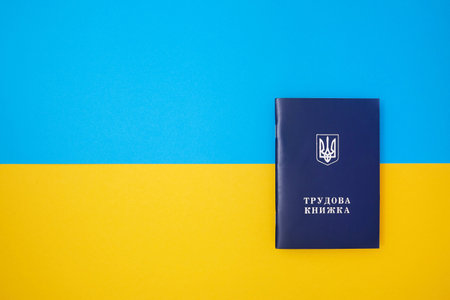 One blue Ukrainian work book on the Ukrainian national flag in the top viewの写真素材