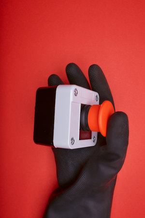 The hand in black resin glove, which pushes the emergency button at the red background at the side viewの写真素材