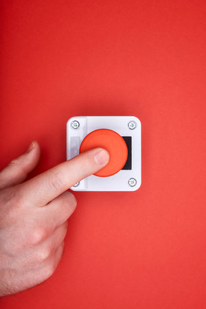 The hand, which pushes the emergency button at the red background at the top viewの写真素材