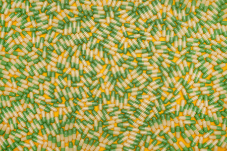 Filled background of green-yellow capsules on yellow backgroundの写真素材