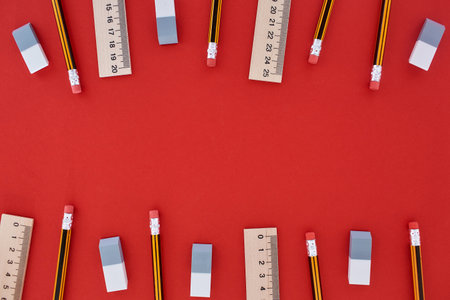 Top and bottom located many pencils, lines and erasers in top view at the red backgroundの写真素材