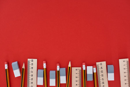 Bottom located many pencils, lines and erasers in top view at the red backgroundの写真素材