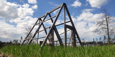 Unfinished forest cabin in the meadow on the background of the blue sky