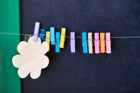 rope with colored clothespins and blank stickers for notes on black schoolboard backgroundの写真素材