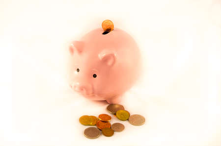 Golden coins falling into a piggy bank isolated on white 