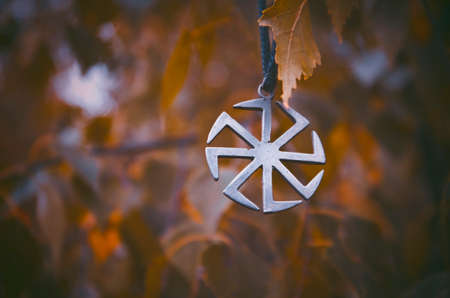 Symbol Kolovrat on the background of birch leaves.