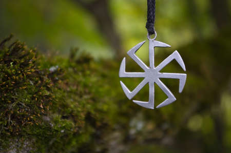 Pagan symbol Kolovrat on the background of moss.の写真素材