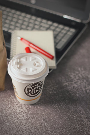 Washington, USA - January 18 2023 : Coffee Cup Mug Burger King with notebook and laptop on gray table In studio lighting, Burger King is a popular food in America.のeditorial素材