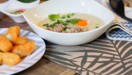 Chinese style porridge or porridge and fried dough stick or fried dough stick or donut or fried bread placed on a wooden table. Thai street food is called "porridge" and "Patongo".の写真素材