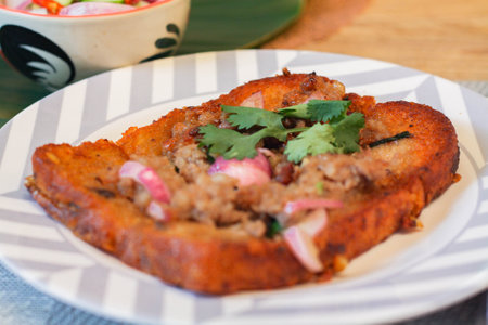 Fried bread with minced pork spread with cucumber dipping sauce on a wooden table. Or as we call it "knom pang na moo"の写真素材