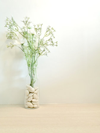 White stones in vase on wooden table and white wall background.の写真素材