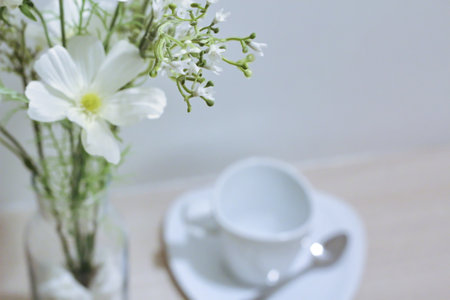White flowers in a vase on the table with a cup of coffee