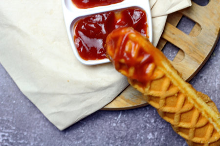 Corn dogs waffle and ketchup on a gray tableの写真素材
