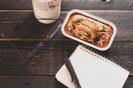Banana Cake on a black wooden table With note book, glasses, and coffee mugs.の写真素材