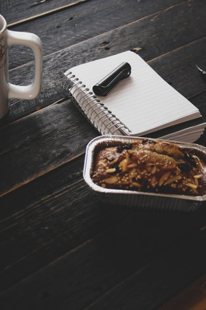 Banana Cake on a black wooden table With note book, glasses, and coffee mugs.の写真素材
