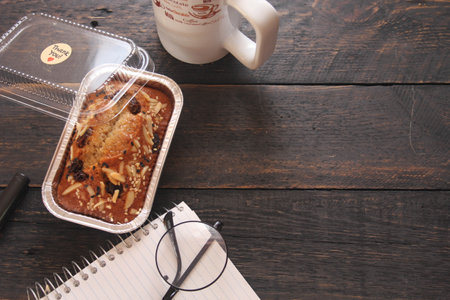 Banana Cake on a black wooden table With note book, glasses, and coffee mugs.の写真素材