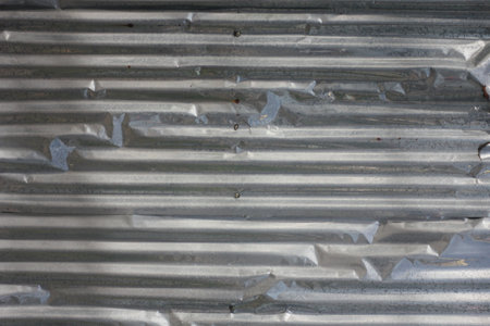 Old galvanized fence with dents and side lighting.の写真素材