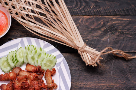 Fried Pork Belly with Fish Sauce and Sticky Rice Served on a white plate on a black wooden floor.の写真素材