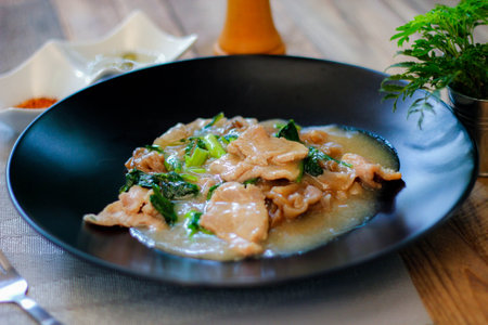Wide Rice Noodles with pork in Gravy Sauce in black Plate or what we call  Rat-na  in Thai, in...