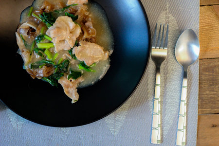 Wide Rice Noodles with pork in Gravy Sauce in black Plate or what we call " Rat-na " in Thai, in thailandの写真素材