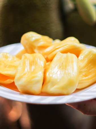 Jackfruit is fresh in a white plate, placed on a wooden table with jackfruit branches in thailand.