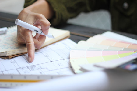 Hands of Asian female engineers are working on construction drawings on site.