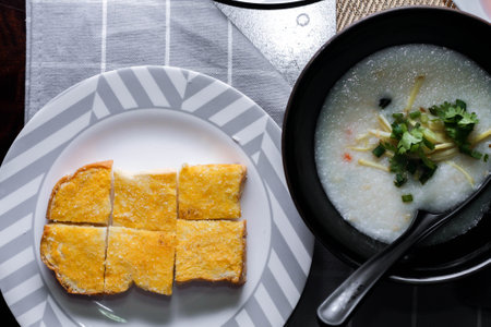 Chinese style porridge or porridge and fried dough stick or fried dough stick or donut or fried bread placed on a brown wooden table. Thai street food called "Porridge" and "Patongko", and toastの写真素材