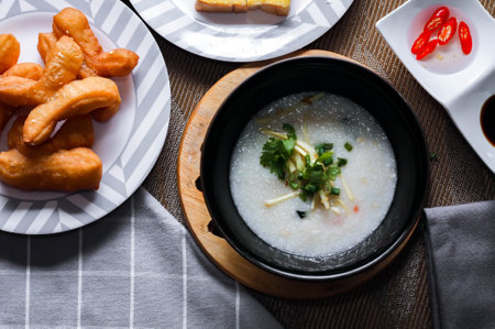 Chinese style porridge or porridge and fried dough stick or fried dough stick or donut or fried bread placed on a brown wooden table. Thai street food called "Porridge" and "Patongko", and toastの写真素材