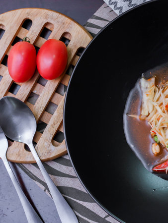 Thai papaya salad or " Somtum " in Thai. The famous local Thai street food dish with the taste of hot and spicy on wood table. Street food in Thailand.の写真素材