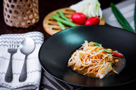 Thai papaya salad or " Somtum " in Thai. The famous local Thai street food dish with the taste of hot and spicy on wood table. Street food in Thailand.の写真素材