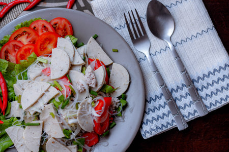 Spicy Glass Noodle Salad with Vietnamese Sausage  served in a gray plate Put on a wooden table and various vegetables.の写真素材