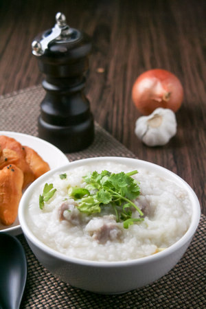 Pork porridge with coriander and ginger or porridge is similar to rice porridge but softer in texture. Served on a wooden table with patongko. For breakfast in the morning or eveningの写真素材
