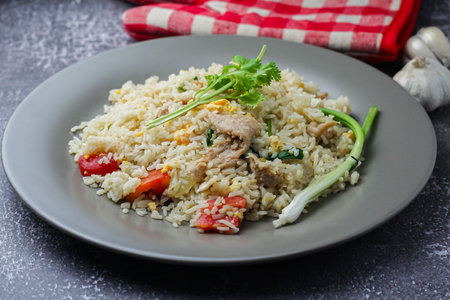 fried rice with chicken and vegetables in a plate on a dark backgroundの写真素材