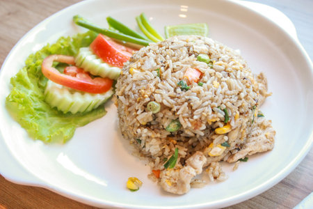 Pork fried rice served in a restaurant with wooden floor tables with tomatoes, cucumbers, scallions, fried rice, delicious food made from steamed rice.の写真素材