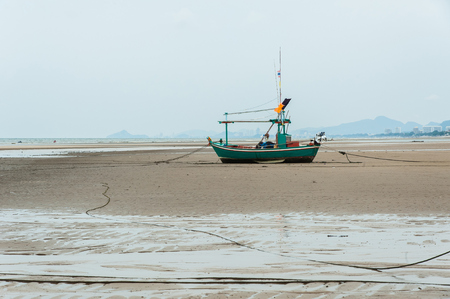 Fishing boat is empty. Parking on the white beach on monsoon day.の写真素材