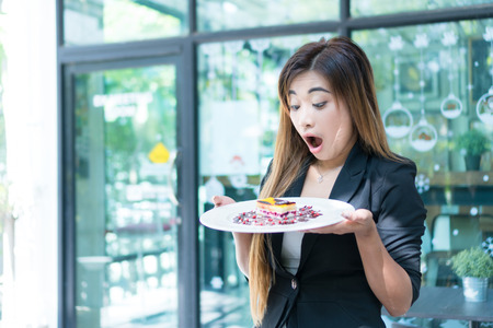 Beautiful girl happy to see the cake she likes. She expresses shocking colors and dance moves. She is very happy to see the cake. selected focus, coffee break, relaxation.の写真素材