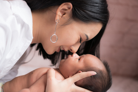 Beautiful Asian mother Kiss and cuddle in the bedroom.の写真素材