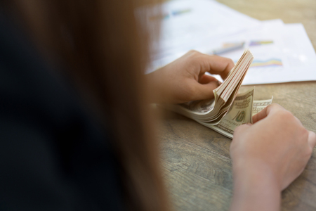 woman hands counting us dollar banknotes. She counts a lot of money.の写真素材